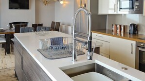 Una cucina moderna con isola centrale, elettrodomestici in acciaio inossidabile e zona pranzo con tavolo e sedie.