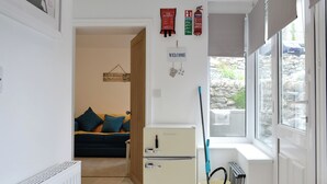 A compact living space with a kitchenette, a door leading to a balcony, and a view of a stone wall outside. - Brig-Y-Don Bach - UK11309 (Llanaber, near Barmouth)
