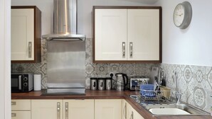 A kitchen with a stainless steel range hood, a microwave, a toaster, and a sink with a dish rack. - Brig-Y-Don Bach - UK11309 (Llanaber, near Barmouth)
