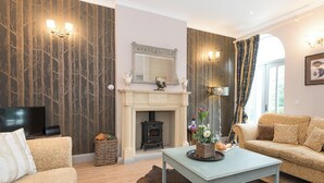 Una sala de estar con chimenea, sofá, televisor y una mesa de comedor.