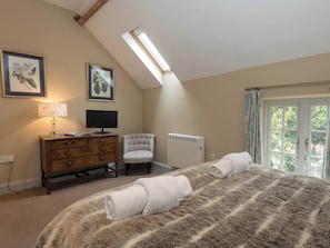 A bedroom with a large bed, a dresser, a chair, a radiator, and a window with curtains. - No.1 Meynell Mews - UK11320 (Breedon on the Hill)