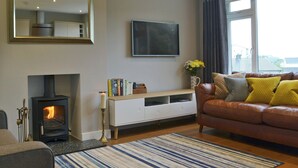 A living room with a fireplace, a sofa, a TV, and a window. - 3 bedroom accommodation in Ambleside (Ambleside)