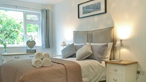 A neatly made bed with rolled towels, a bedside lamp, a small bedside table, and a picture on the wall. - 3 bedroom accommodation in Ambleside (Ambleside)