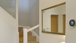 A staircase with wooden steps and white railings, a wall-mounted mirror, and a thermostat displaying 19 degrees. - 3 bedroom accommodation in Ambleside (Ambleside)