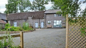 A gravel courtyard with wooden buildings, a wooden deck, and a lattice fence. - 1 bedroom accommodation in Garth, near Builth Wells (Garth, near Builth Wells)