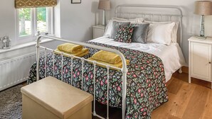 A bedroom with a bed, bedside tables, a window with curtains, a radiator, and a bench. - 1 bedroom accommodation in Garth, near Builth Wells (Garth, near Builth Wells)