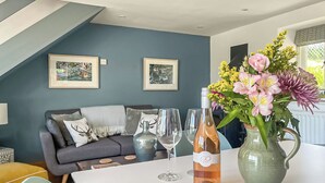 A modern living room with a sofa, a dining table with wine glasses and a bottle, and two framed pictures on the wall. - 1 bedroom accommodation in Garth, near Builth Wells (Garth, near Builth Wells)