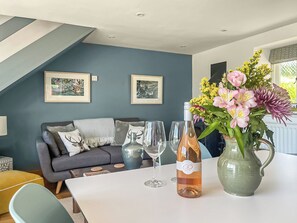 A modern living room with a sofa, a dining table with wine glasses and a bottle, and two framed pictures on the wall. - 1 bedroom accommodation in Garth, near Builth Wells (Garth, near Builth Wells)