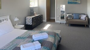 Ein Schlafzimmer mit Bett, Schminktisch, Nachttisch, Lampe und einer Couch.