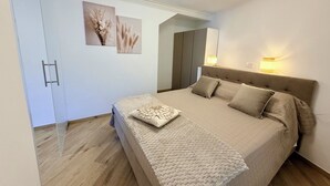 A bedroom with a bed, bedside lamps, a wardrobe, and two wall-mounted pictures. - Zaffiro - Apartment with Lake View Balcony, near Bellagio (Lezzeno)