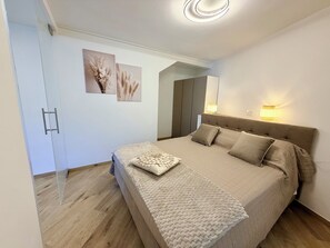 Ein Schlafzimmer mit einem Bett, Nachttischlampen, einem Kleiderschrank und zwei Wandbildern.