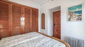 Ein Schlafzimmer mit einem großen Bett, einem Holzschrank, einem Heizkörper und einem an der Wand befestigten Spiegel.