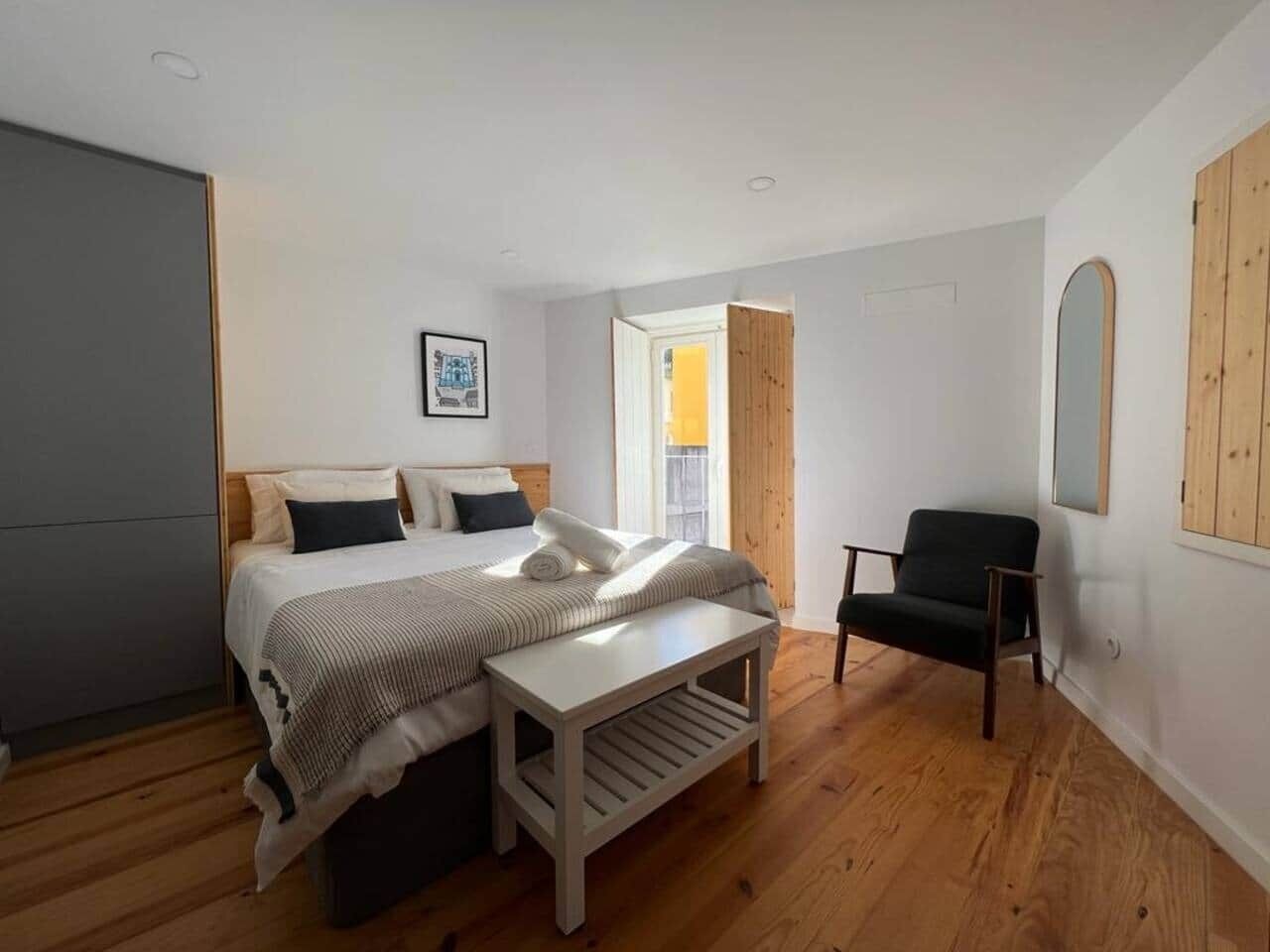 Une chambre à coucher comprenant un lit, un banc, une chaise et une porte donnant sur une autre pièce.