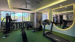 A gym with exercise equipment, a treadmill, and a large mirror.
