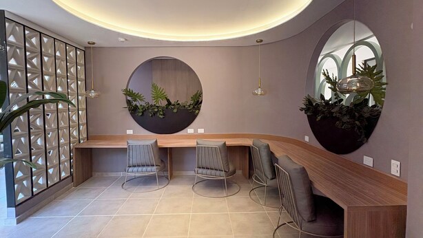 A modern interior with a curved ceiling, a wooden reception desk, and a round table with chairs.