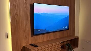 Een flatscreen televisie bevestigd aan een houten wand, met een afstandsbediening op een houten plank eronder.