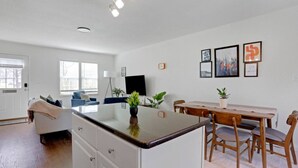 Cocina moderna con una isla central, una mesa de comedor y sillas. Hay plantas en macetas sobre la isla y la mesa.