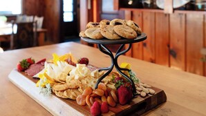 A wooden interior with a wooden table displaying a variety of snacks and a decorative metal stand. - Island view Crooked Lake cottage, 170' frontage, best views! (Alanson)