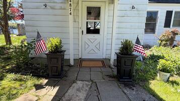 A house with a white exterior, a porch with a roof, and a door with a number '4874' on the wall.