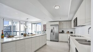 Cozinha moderna com uma ilha grande, eletrodomésticos de aço inoxidável e vista para a cidade.