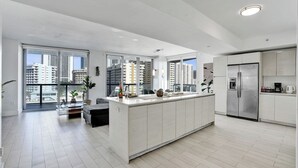 Cozinha moderna com ilha central, janelas amplas e vista para edifícios altos.