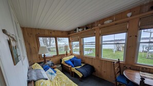 A cabin with a wooden interior, a dining table, and a view of a lake. - Lake House getaway!!! 2-bedroom Cayuga Lake, lake front property! (Seneca Falls)