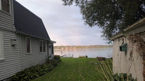 A residential property with a grassy yard, a dock extending into a lake, and a house with a dark roof. - Lake House getaway!!! 2-bedroom Cayuga Lake, lake front property! (Seneca Falls)