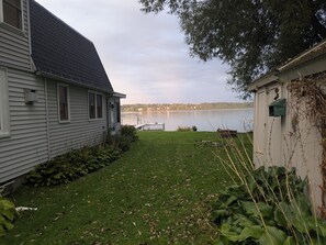 A residential property with a grassy yard, a dock extending into a lake, and a house with a dark roof. - Lake House getaway!!! 2-bedroom Cayuga Lake, lake front property! (Seneca Falls)