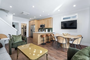 Una cocina moderna con una isla central, taburetes de bar y una mesa de comedor con sillas.