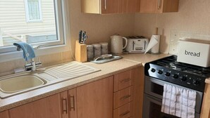 Eine Küche mit Holzausstattung, einem Spülbecken, einem Herd und einem Toaster.