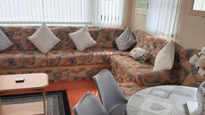 Ein Wohnzimmer mit einem gemusterten Sofa, einem kleinen Tisch und einem Sessel.