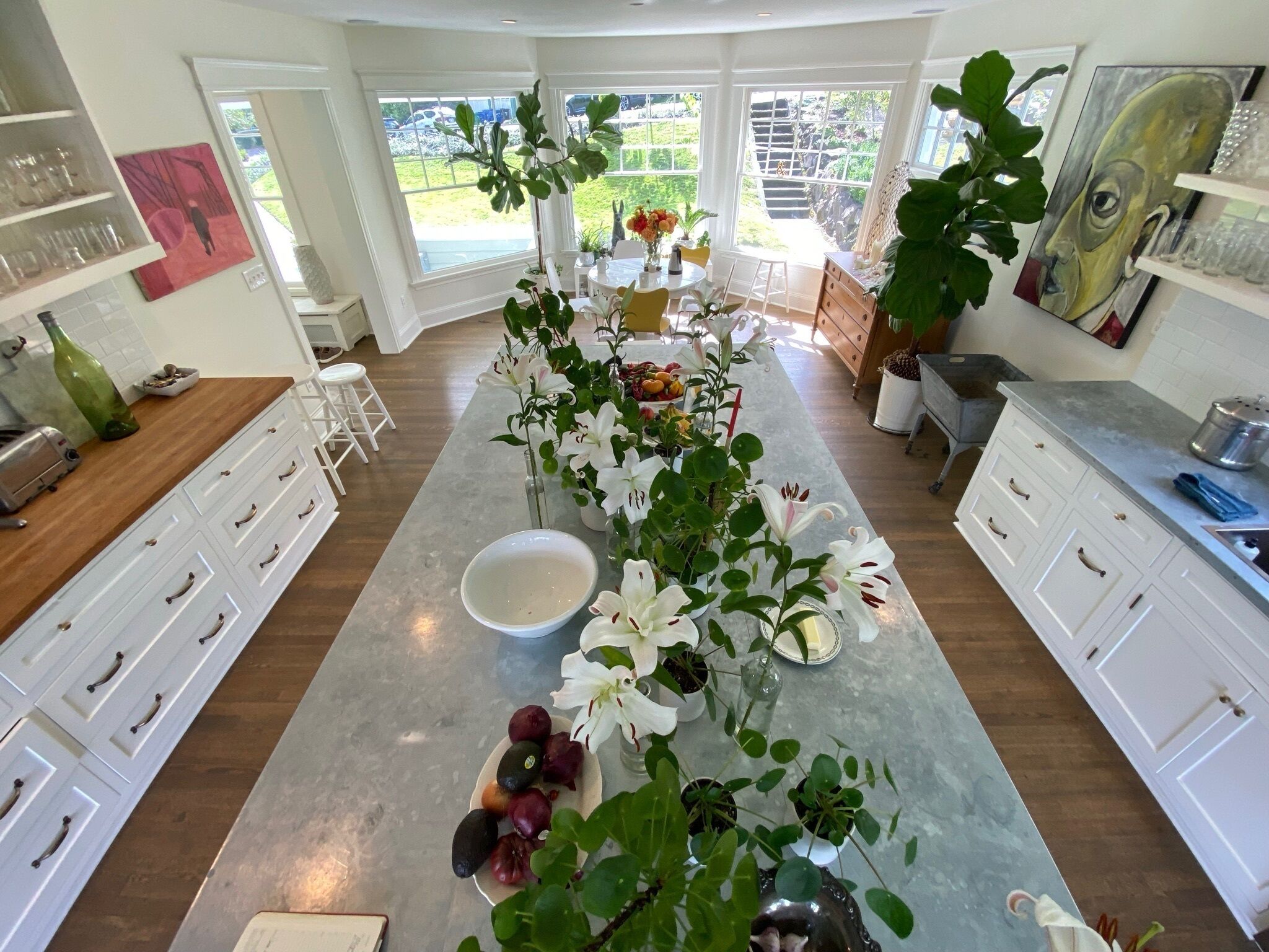 A kitchen with a central island, white cabinetry, and a view of the outdoors.