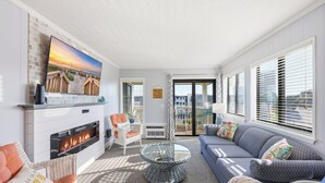 Ein Wohnzimmer mit Kamin, einer Couch, einem Glastisch und einem an der Wand befestigten Fernseher.