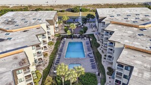 Ein Hotel mit zentralem Schwimmbad, mehreren Balkonen und Blick auf den Strand.