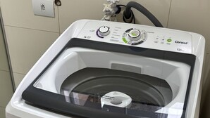 A front-loading washing machine with a control panel, a water inlet, and a drain hose. - Ravello Residential AP01 Foz do Iguaçu (Foz do Iguaçu)