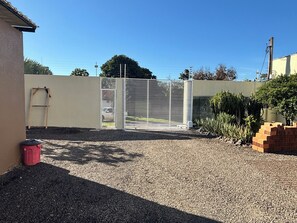 A gravel driveway leading to a gated entrance with a metal gate and a ladder leaning against a wall. - Ravello Residential AP01 Foz do Iguaçu (Foz do Iguaçu)
