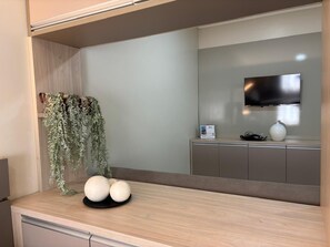 Eine moderne Küche mit einer Holzausziehtheke, einer hängenden Pflanze und einem an der Wand befestigten Flachbildfernseher.