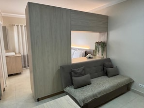 Une chambre moderne avec un canapé, un miroir et une plante.