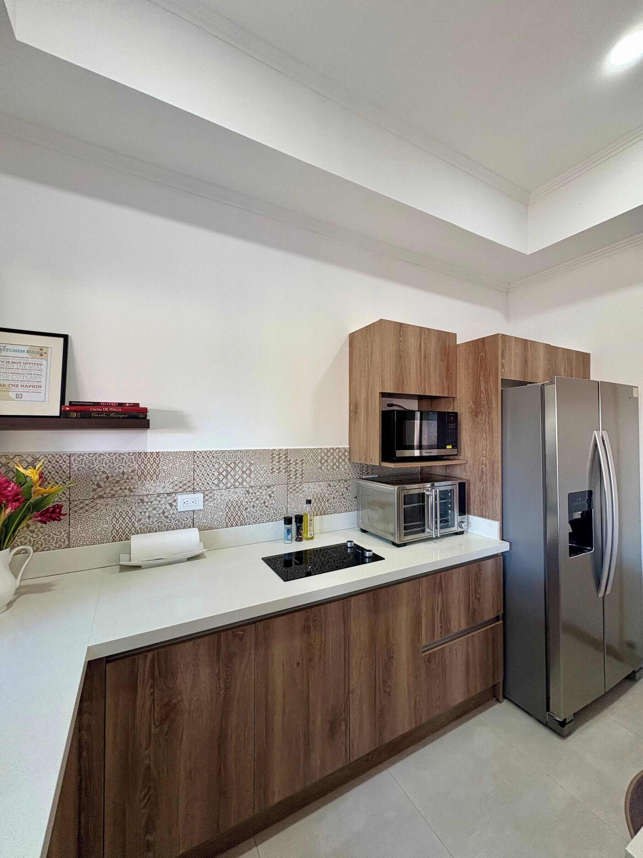 Cucina moderna con mobili in legno, frigorifero in acciaio inossidabile, microonde e tostapane.