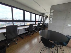 Ein moderner Büroraum mit großen Fenstern, einem Konferenztisch und Bürostühlen.