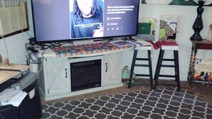 A room with a television on a stand, a patterned rug, a sofa, and a chair.