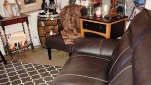 A brown leather sofa with a patterned rug, a small side table with a vase, and a framed picture on the wall.