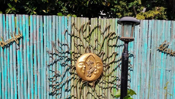 A bamboo fence with decorative elements, a metal sign with 'thankful,' and a street lamp.