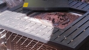A portable heater with a metal grate and a control panel, placed on a brick surface.