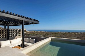 Ein Pool auf dem Dach mit einer weißen Sitzgelegenheit im Freien und Blick aufs Meer.