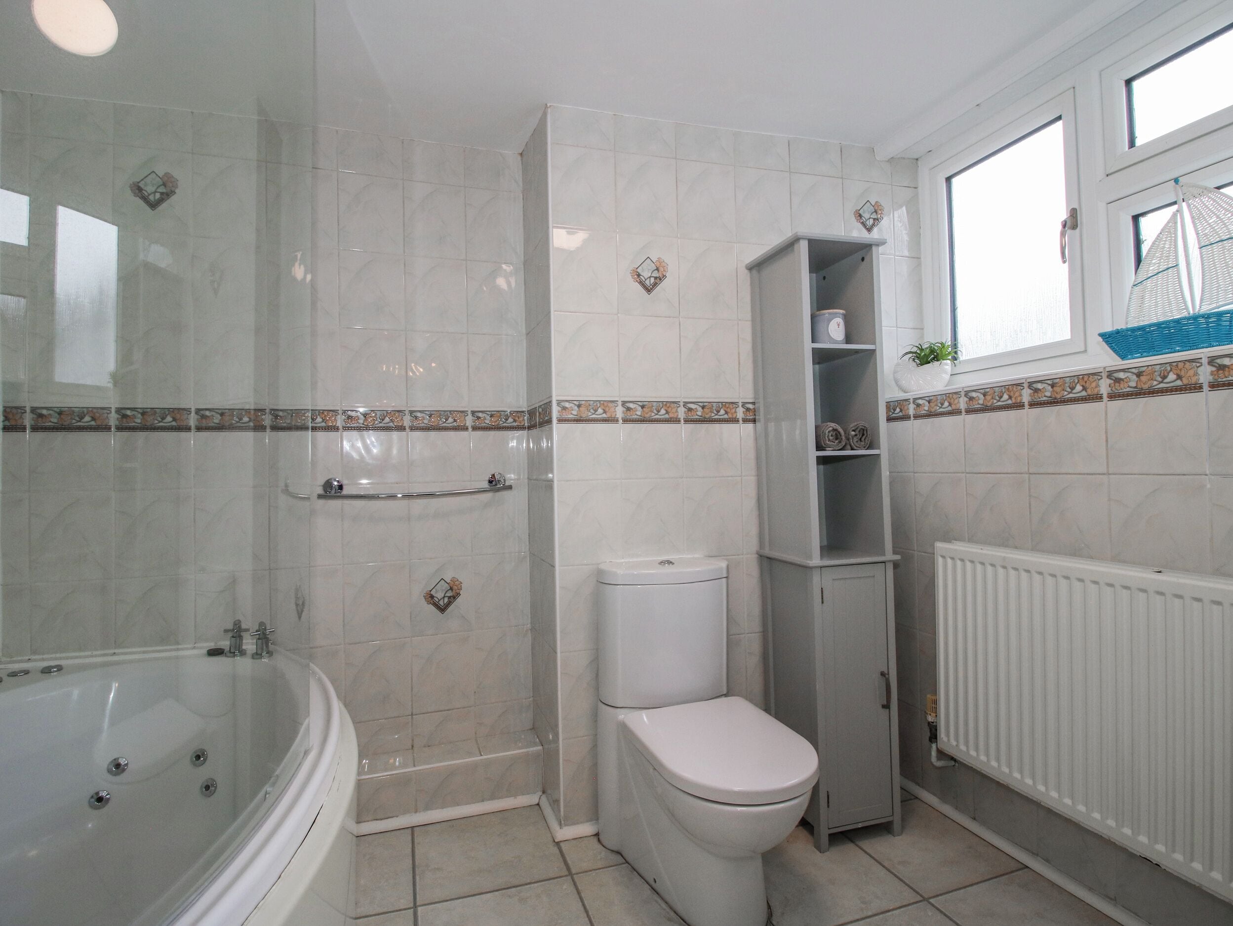Une salle de bain avec une baignoire, des toilettes et une étagère.