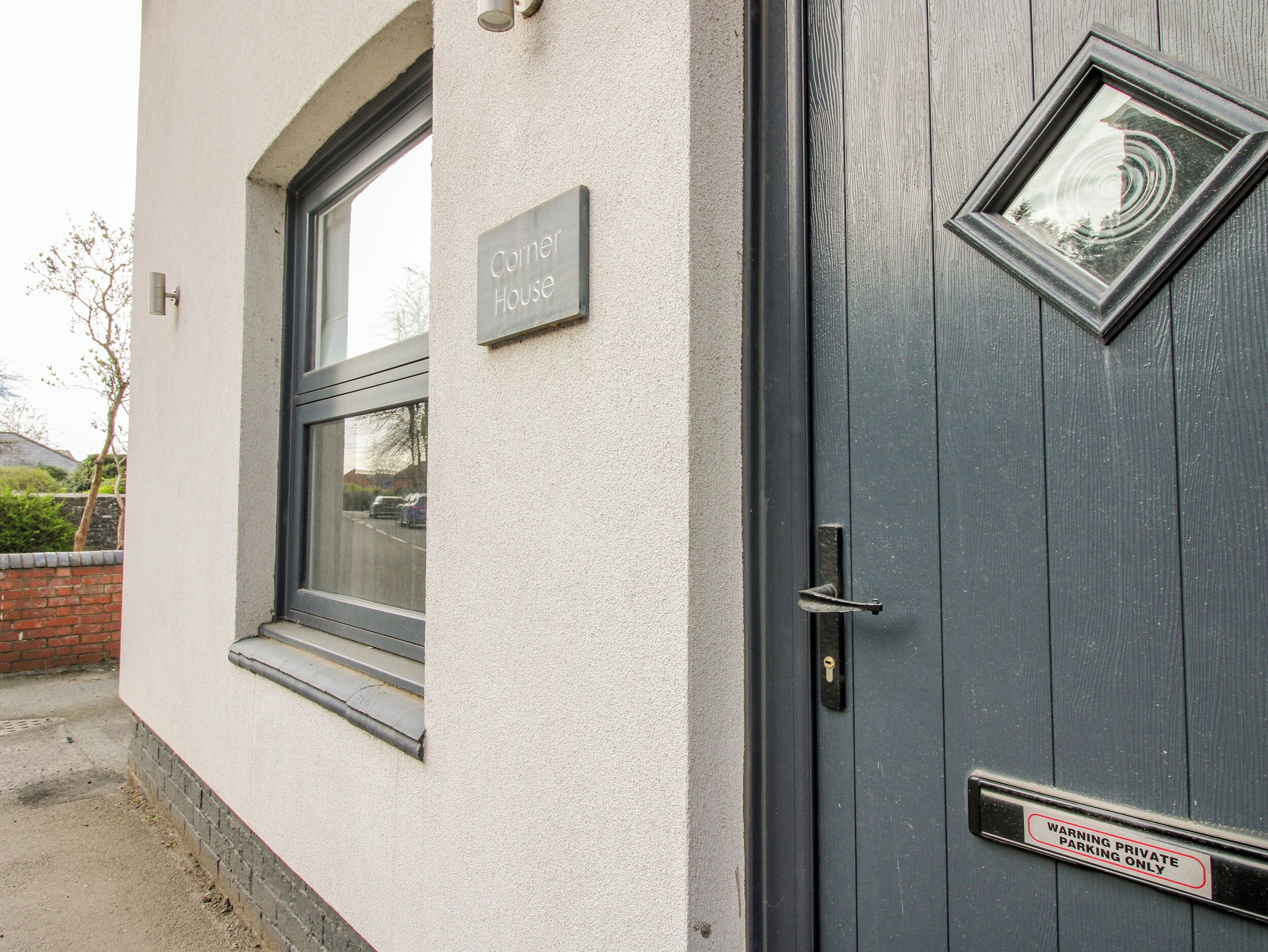 Un edificio con un letrero que dice 'Corner House' y una puerta con un rótulo que indica 'ESTACIONAMIENTO PRIVADO, SOLO AUTORIZADO'.