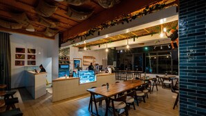 Een restaurant met houten tafels, een balie en hangende planten.