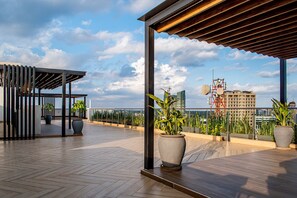 A rooftop terrace with wooden flooring, potted plants, a pergola, and a cityscape view. - Marina Bay  (Nairobi)