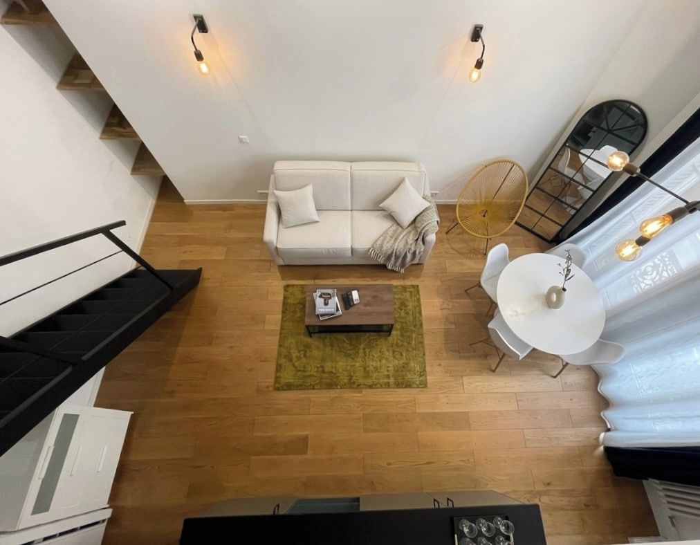 A modern living room with a sofa, coffee table, and a dining area with a chair and table.